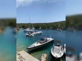 A picturesque view of several boats anchored in a serene bay, with guests enjoying the beautiful coastal scenery — perfect for a summer getaway.