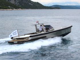 A sleek WALLY speedboat cuts through the water, showcasing its design and performance with crew on board, perfect for thrilling adventures on the open sea.