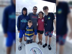 A cheerful family poses together on a boat, ready for a fun day on the water — perfect for family outings and adventures.