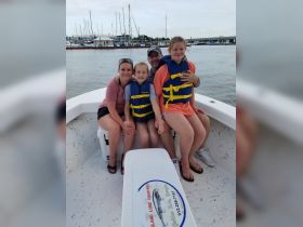 A cheerful family poses on a boat, all wearing life jackets, ready for a fun day on the water — perfect for family outings and adventures.
