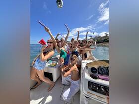 A lively group of friends celebrates aboard a boat, enjoying a fun-filled day with drinks and laughter under the sun.