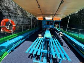 Interior view of a colorful boat cabin featuring ample seating and a life ring, perfect for group excursions or sightseeing tours.
