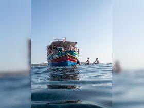A vibrant boat filled with guests enjoying a sunny day on the water, creating a lively atmosphere perfect for summer adventures.