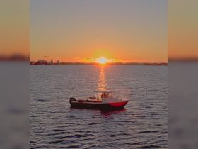 A serene sunset view featuring a small boat anchored in calm waters, creating a picturesque scene perfect for relaxation and evening cruises.