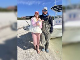 A cheerful couple poses by their boat on the beach, celebrating a day of fun in the sun. Perfect for showcasing memorable moments during a boating adventure.