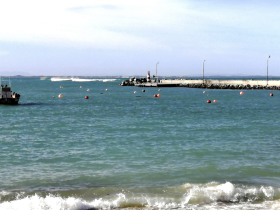 A view of the water with a distant boat and a rocky pier, but the image lacks clarity and detail.