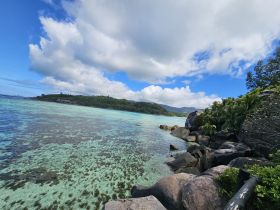A stunning view of a serene coastline with clear turquoise waters and lush greenery, perfect for showcasing the natural beauty of island destinations.