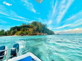 A stunning view of a lush island coastline with turquoise waters, perfect for showcasing the beauty of tropical destinations and boating adventures.