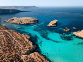 A stunning aerial view of a picturesque coastline featuring turquoise waters and rocky islands, perfect for exploring by boat.