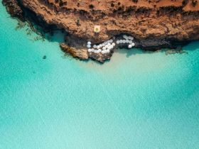 A stunning aerial view of a secluded beach with turquoise waters and white umbrellas, perfect for relaxing and enjoying the natural beauty of the coastline.