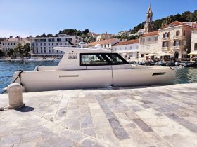 A sleek yacht docked at a picturesque harbor, showcasing its modern design against a charming coastal backdrop.