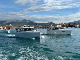A scenic view of multiple boats cruising along the coastline, showcasing a vibrant boating experience against a picturesque backdrop.