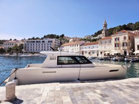 A sleek yacht docked at a picturesque harbor, showcasing the charming architecture of the waterfront buildings and clear blue skies.