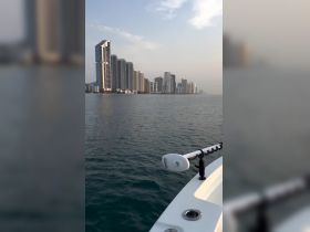 A scenic view of a boat navigating through calm waters with a stunning city skyline in the background, perfect for urban boating adventures.