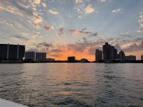 A stunning sunset over the skyline, reflecting on the water, creating a picturesque backdrop for evening boat trips.