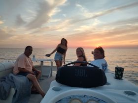 A group of friends enjoys a beautiful sunset on a boat, capturing memories with smiles and laughter — the perfect backdrop for a memorable evening on the water.