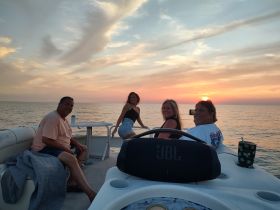 A cheerful group enjoys a sunset cruise on a pontoon boat, capturing the perfect moment of relaxation and celebration on the water.