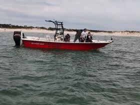 A group of friends enjoys a fishing trip on a Blazer Bay boat, showcasing the excitement of reeling in a catch in beautiful waters.