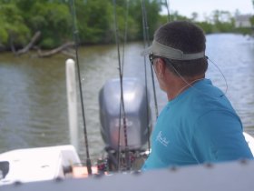 A man on a fishing boat looks out over the water, ready for a day of fishing in a serene environment.
