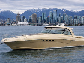 A stunning yacht glides through the water with a backdrop of the Vancouver skyline and snow-capped mountains, showcasing the beauty of luxury boating.