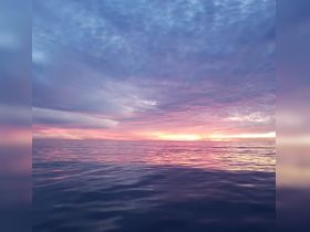 A stunning sunset over calm ocean waters, showcasing vibrant colors and serene beauty — perfect for capturing the essence of a peaceful evening at sea.