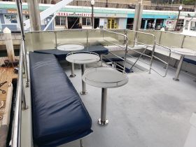 Interior view of a boat's lounge area featuring comfortable seating and tables, perfect for relaxing during a cruise.