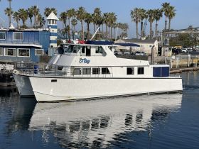 The 'El Rey' yacht is docked, showcasing its sleek design against a backdrop of palm trees and marina scenery.