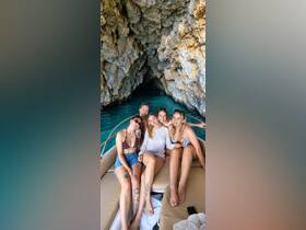 A joyful group of friends poses for a photo inside a boat near a stunning cave, capturing the essence of adventure and camaraderie on the water.