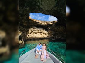 A couple enjoys a picturesque moment on a boat, framed by a stunning natural cave and crystal-clear waters — perfect for romantic getaways and scenic adventures.
