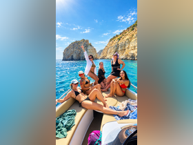 A lively group of friends enjoys a sunny day on a boat, celebrating with laughter and fun against a stunning coastal backdrop.