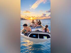 A lively group enjoys drinks on a boat at sunset, capturing the essence of summer celebrations on the water.