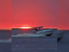 A boat speeds across the water at sunset, creating a stunning silhouette against the vibrant sky — an ideal scene for adventure and exploration on the water.