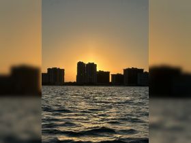A stunning sunset casts a golden glow over the skyline, creating a picturesque backdrop for evening boat trips along the coastline.