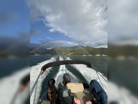 A group enjoys a scenic boat ride under a vibrant rainbow, showcasing the beauty of nature while cruising on the water.