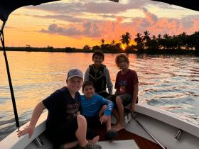 A group of children enjoys a beautiful sunset on a boat, capturing a memorable moment of fun and adventure on the water.
