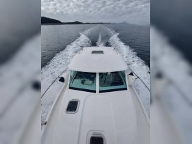 Aerial view of a sleek boat cruising through calm waters, showcasing its elegant design and the serene landscape in the background.