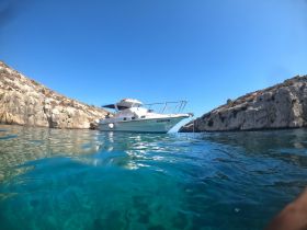 A picturesque view of a boat anchored near rocky cliffs, surrounded by crystal-clear waters, perfect for exploring coastal destinations.