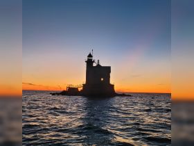 A stunning sunset silhouette of a lighthouse standing against the vibrant sky, capturing the serene beauty of coastal scenery.