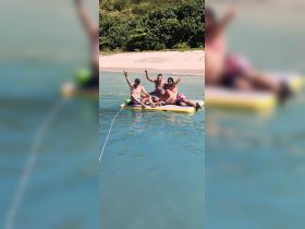 A lively group of friends enjoys a fun day on an inflatable in the clear waters, perfect for beach parties and summer adventures.