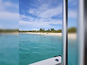 A picturesque view of a beach with people enjoying the clear turquoise waters, perfect for a sandbar stop or a relaxing day in the sun.