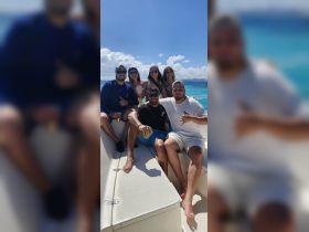 A lively group of friends enjoys a sunny day on the water, celebrating with drinks aboard a boat — perfect for memorable outings and adventures.