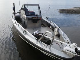 A sleek fishing boat captured from the front, showcasing its design and features while docked on calm waters.