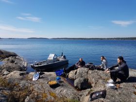 A group enjoys a relaxing day by the water, cooking outdoors near their boat, surrounded by stunning scenery — perfect for a day of adventure and leisure.