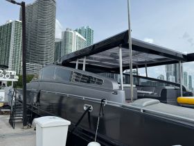 A sleek yacht docked at a marina, showcasing its modern design against a backdrop of towering city buildings.