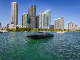A sleek yacht glides through the turquoise waters, framed by a stunning skyline of modern high-rises, showcasing the perfect blend of luxury and urban scenery.