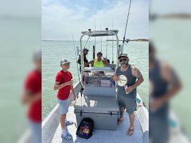 A cheerful group enjoys a fishing trip on a boat, showcasing family fun and camaraderie on the water.