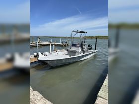 A sleek speedboat docked at a pier, surrounded by calm waters and a clear blue sky, perfect for fishing or leisure outings.