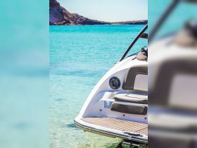 A close-up view of the back of a speedboat docked in crystal-clear turquoise waters, showcasing its sleek design and inviting atmosphere.