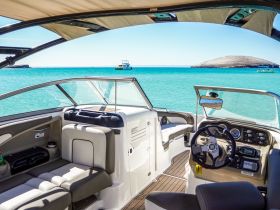 A well-appointed helm area inside a boat, showcasing comfortable seating and a clear view of the turquoise waters outside — perfect for navigating sunny days on the water.