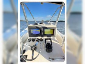 A detailed view of the helm and console of a boat, showcasing the steering wheel and navigation screens, perfect for those interested in boating technology and interior design.